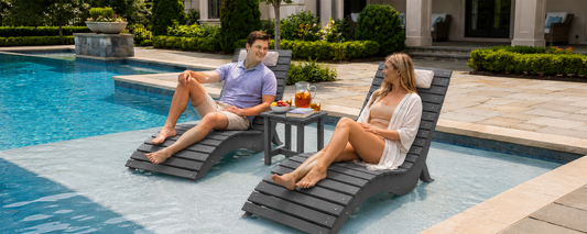 Couple relaxing on easy-clean in-pool lounge chairs with a side table on a shallow tanning ledge