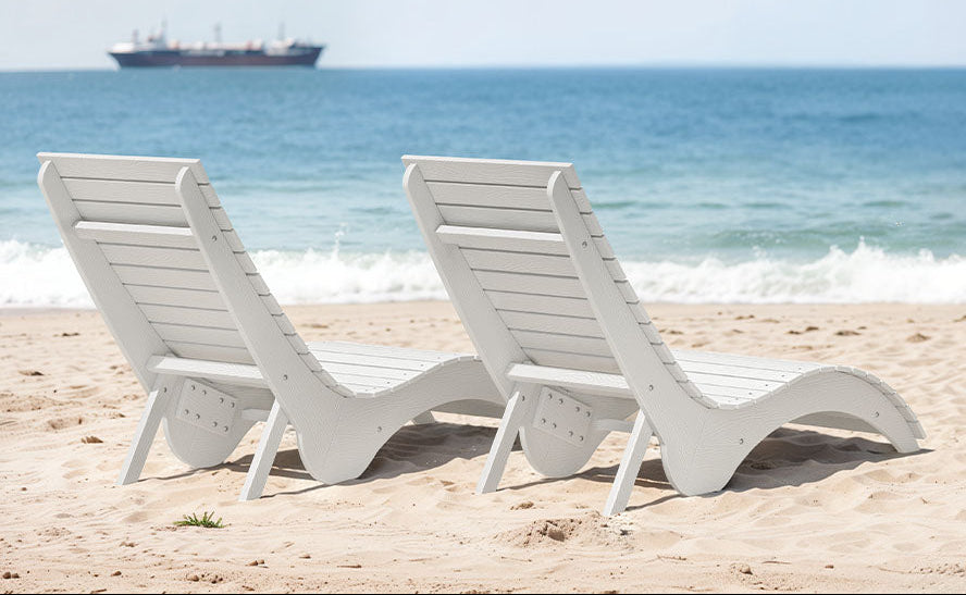 White outdoor lounge chairs on sand showing sturdy, wide-base design